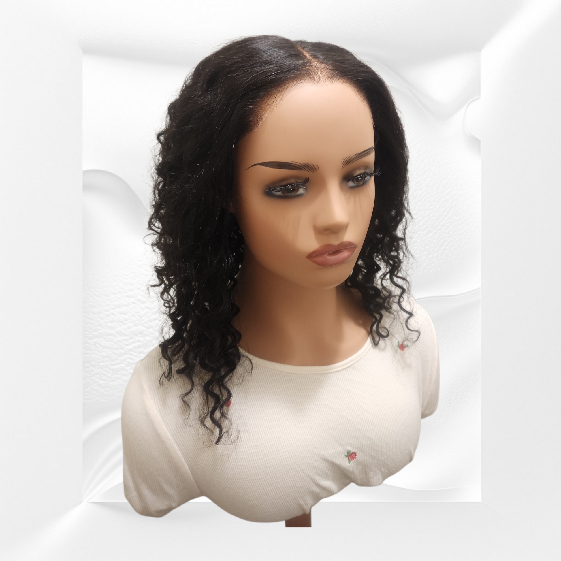 Mannequin head with a black curly wig on a white background