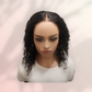 Mannequin head with black curly hair on a light pink background