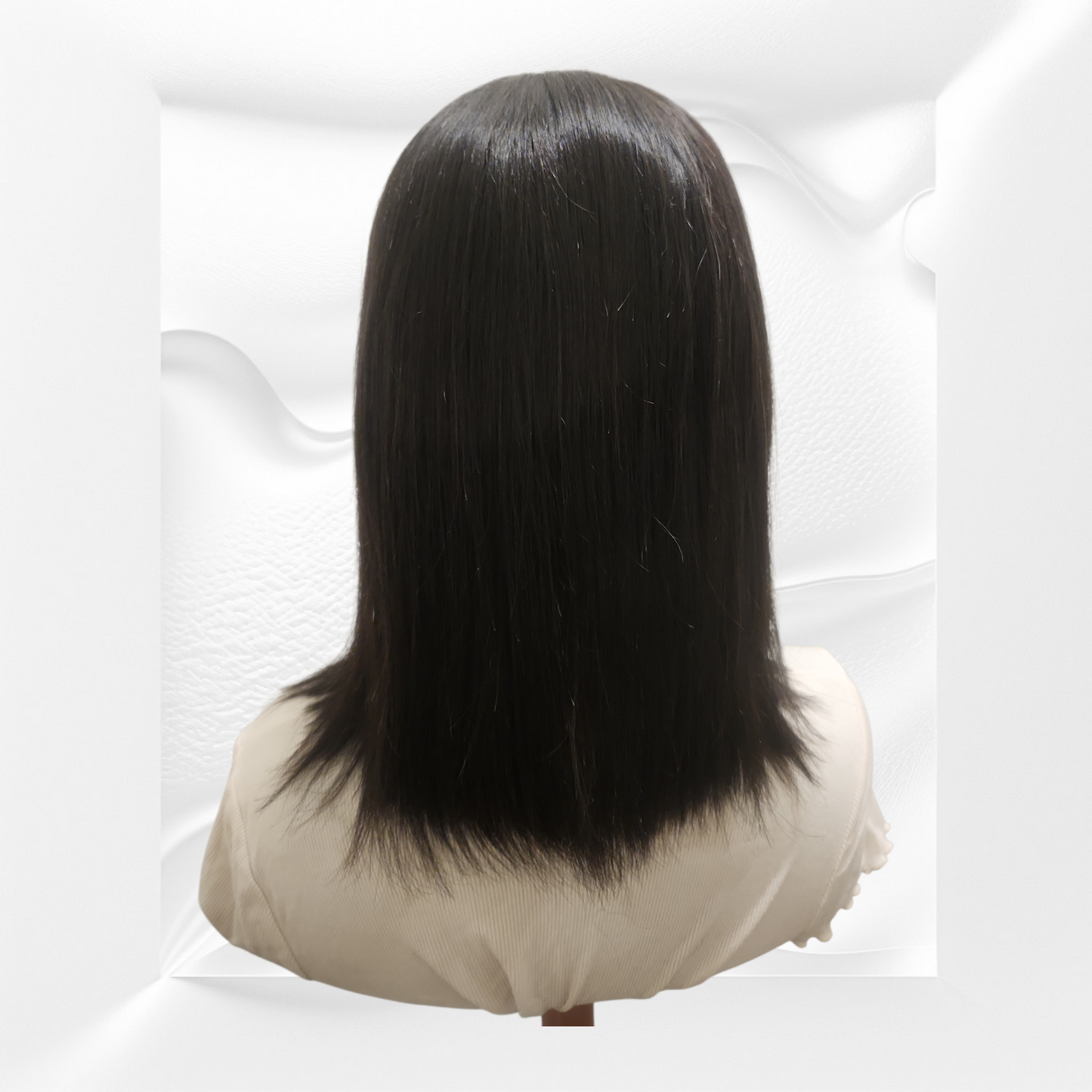 Black wig on a mannequin head against a white background