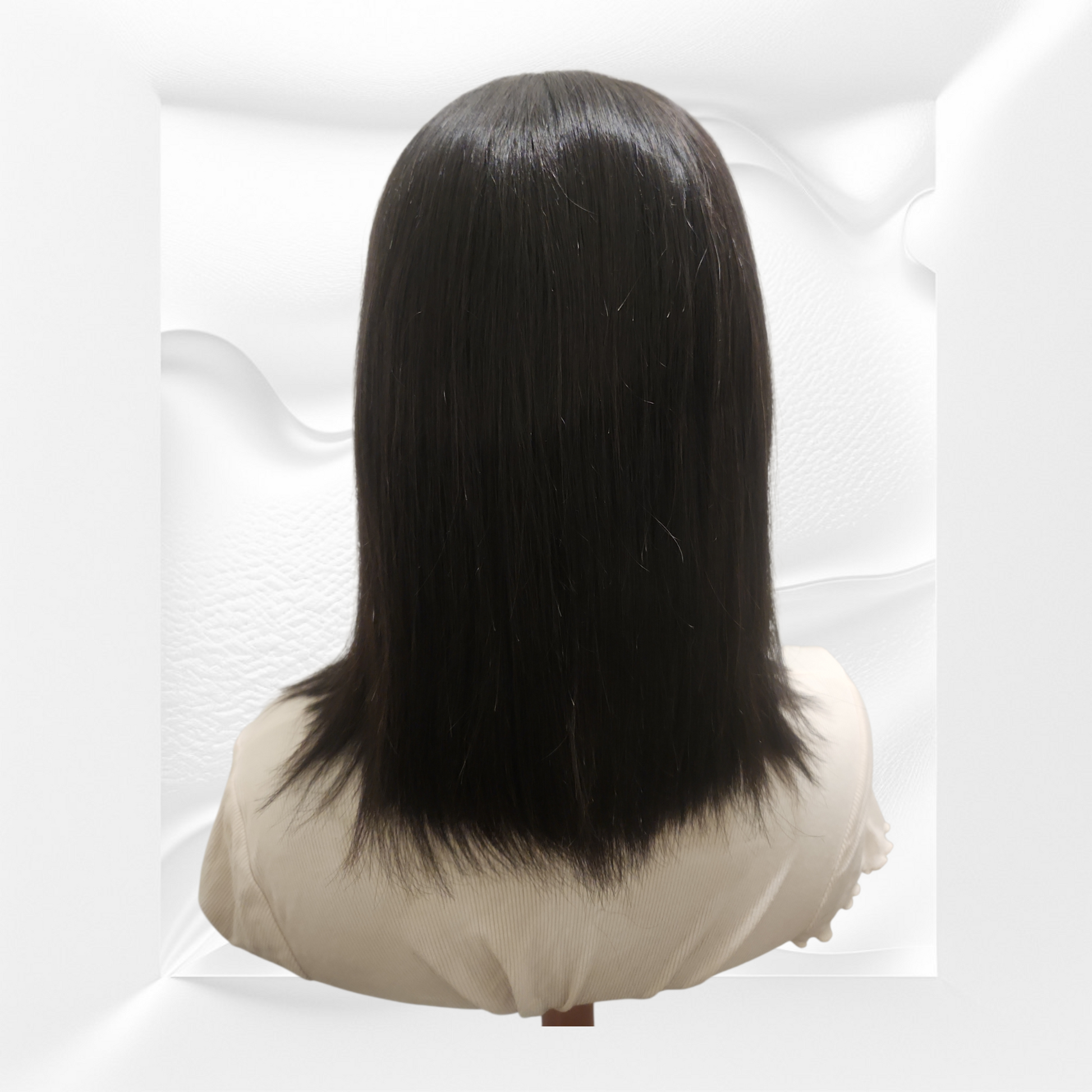 Black wig on a mannequin head against a white background