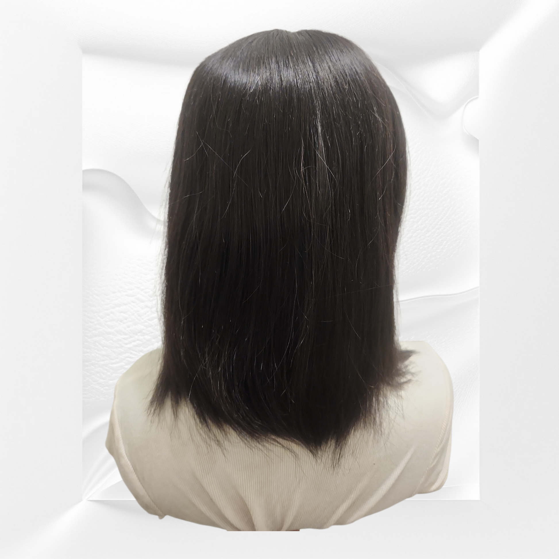 Black wig on a mannequin head against a white background